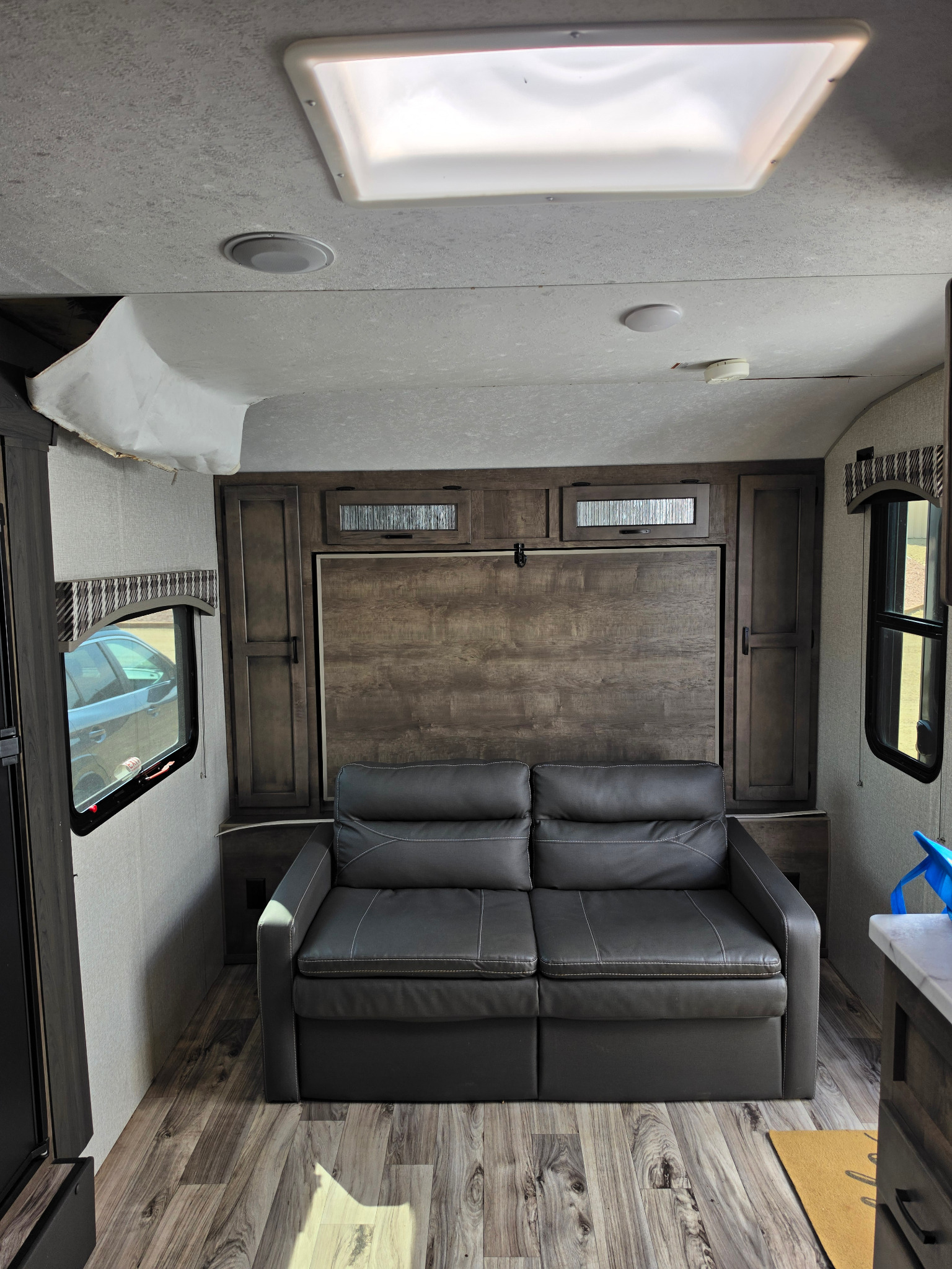Wide interior view showing detached ceiling material in the front corner of the RV
